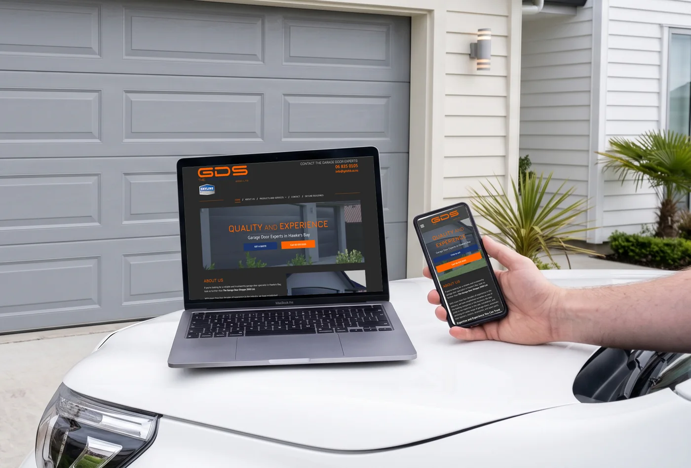 The Garage Door Shoppe website on a laptop and a phone, in front of a garage door